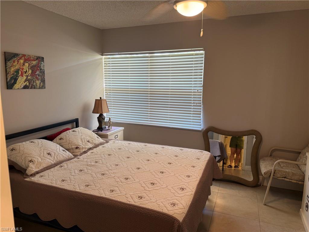 Bedroom with a textured ceiling, ceiling fan, and light tile patterned flooring
