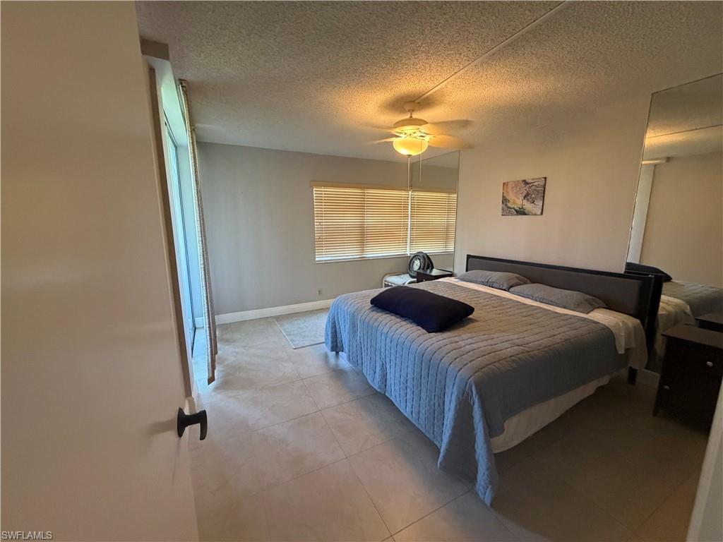 Bedroom with a textured ceiling, ceiling fan, and light tile patterned floors