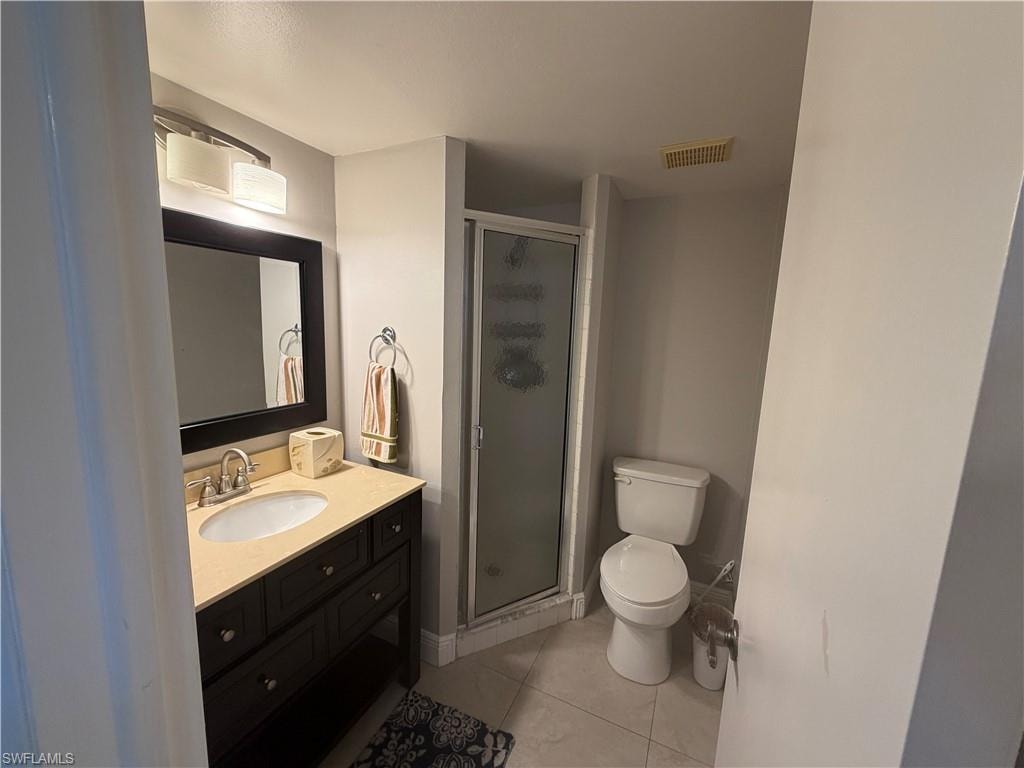 Full bathroom featuring vanity, a stall shower, and light tile patterned floors
