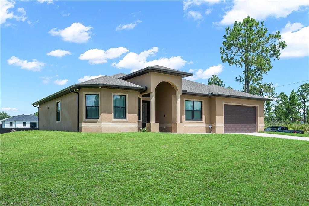 Contemporary stucco exterior with an arched entryway, dark-framed windows, an attached two-car garage, and a manicured lawn