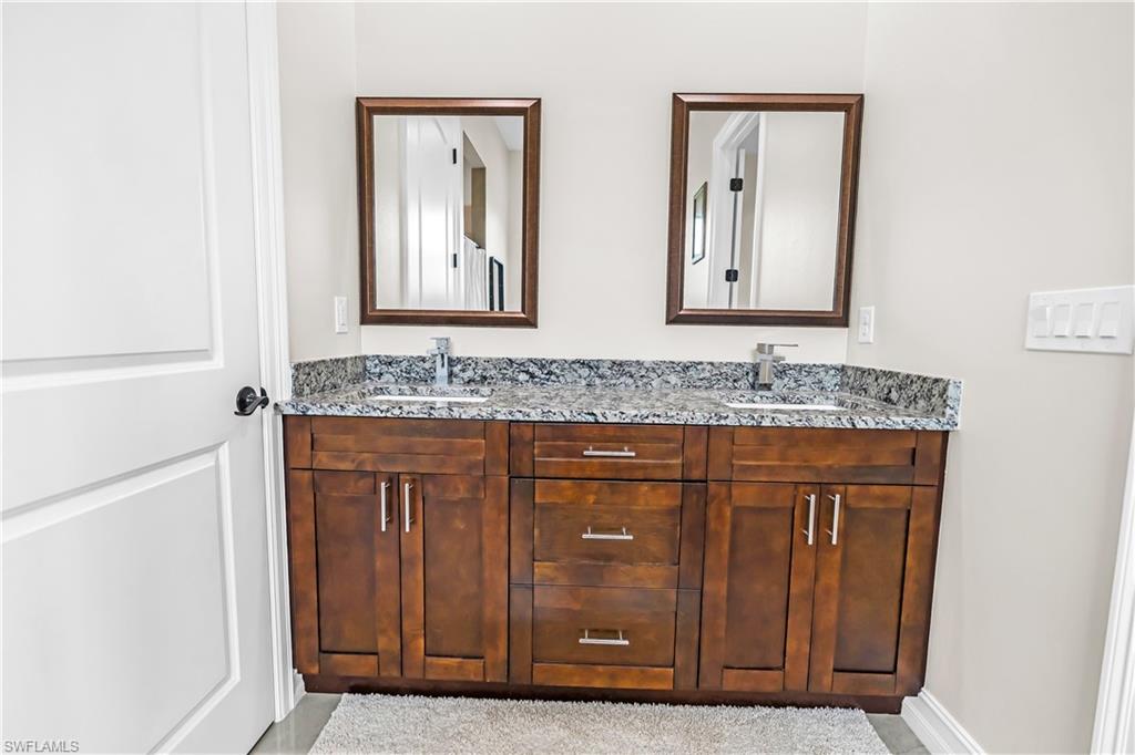 Double vanity with wood-finish cabinetry, integrated sinks, and granite countertops