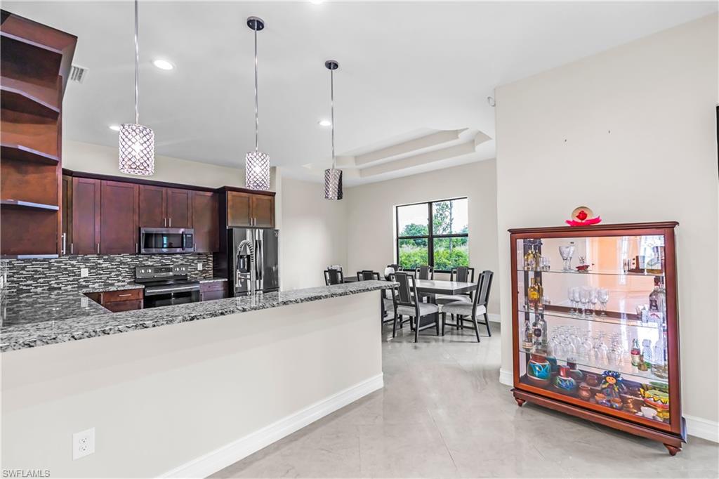 Kitchen featuring a granite-finish breakfast bar, dark wood cabinetry, and stainless steel appliances