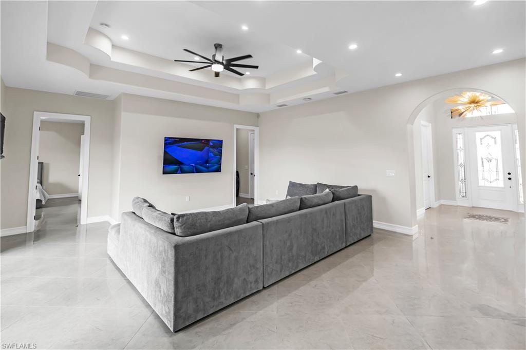 Spacious interior with polished tile flooring, tray ceiling with recessed lighting, and a contemporary ceiling fan