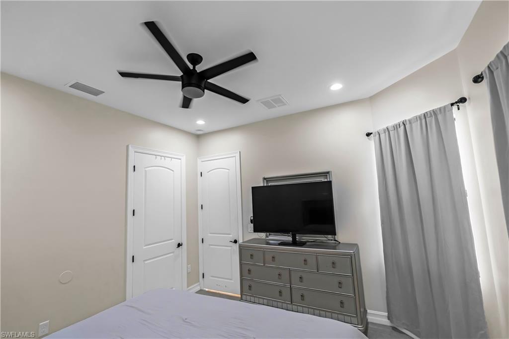 Recessed lighting illuminates a ceiling fan with black blades and a light-toned ceiling