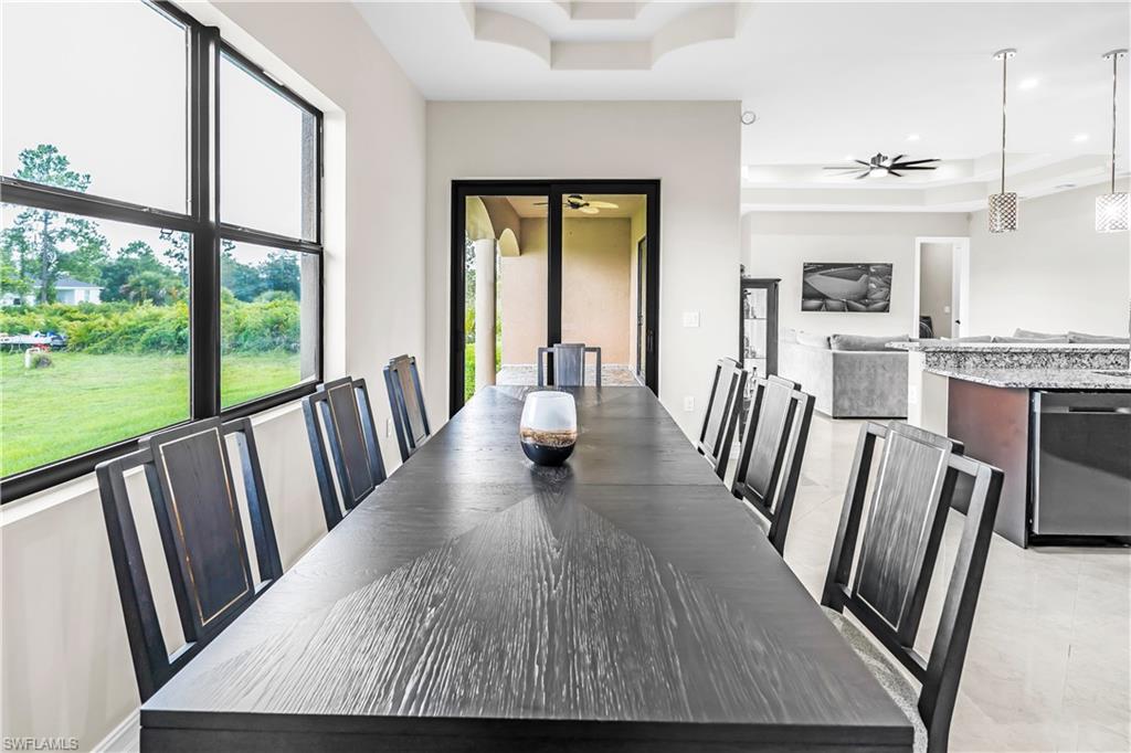 Dining area featuring large windows, recessed ceiling detail, tile flooring, and direct access to an outdoor living space