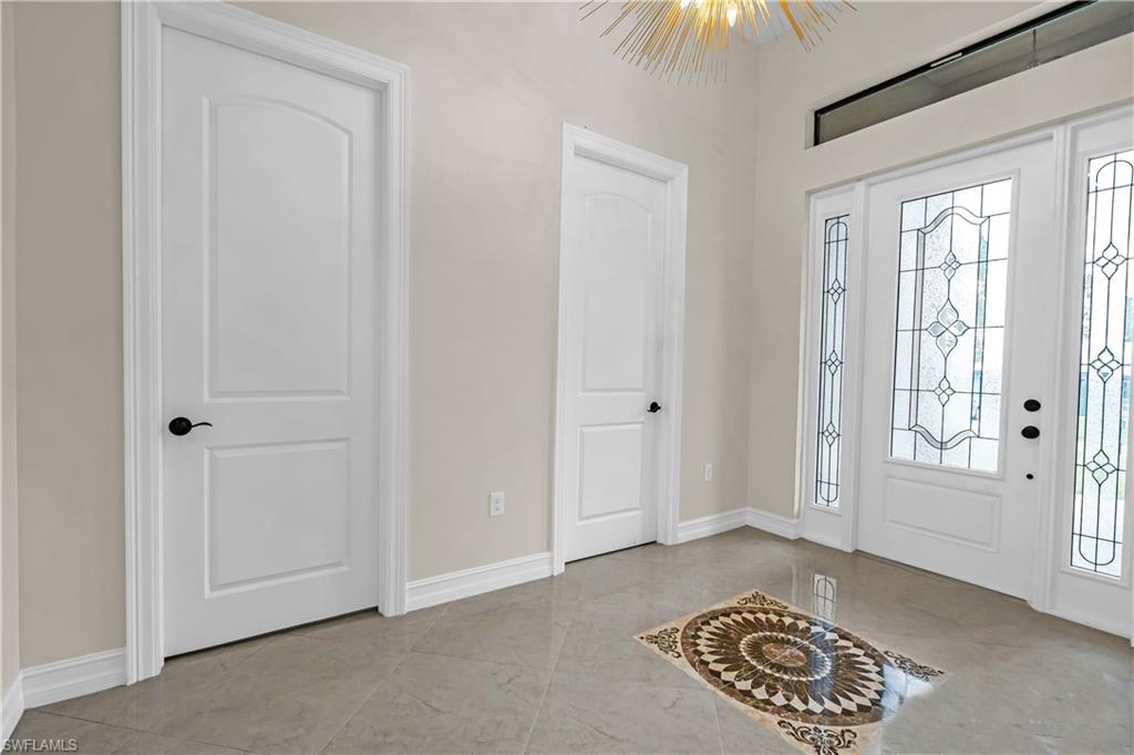 Entryway featuring a decorative inlaid floor medallion, large format tile flooring, and a transom window above the main entry