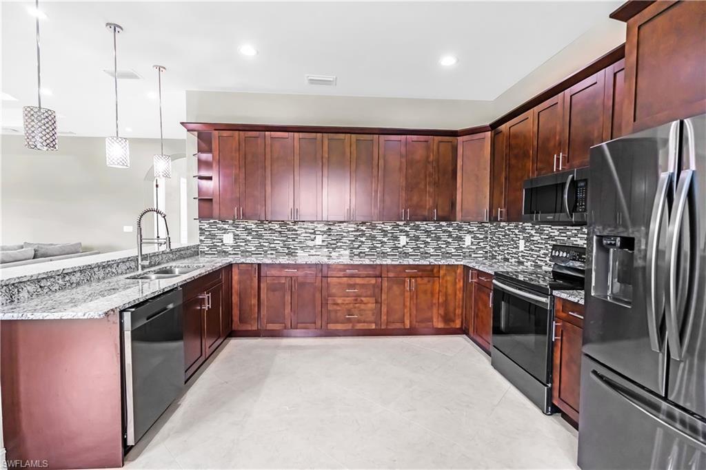 Kitchen featuring dark wood cabinetry, granite countertops, and a mosaic tile backsplash