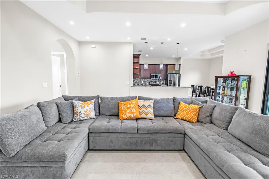 Open-concept living area featuring light-colored flooring, recessed lighting, and a tray ceiling