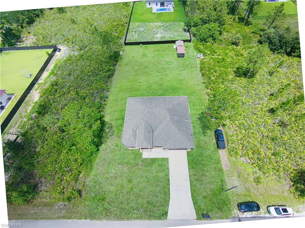 Single-story residence on a spacious, grassy lot featuring a paved driveway and mature perimeter landscaping