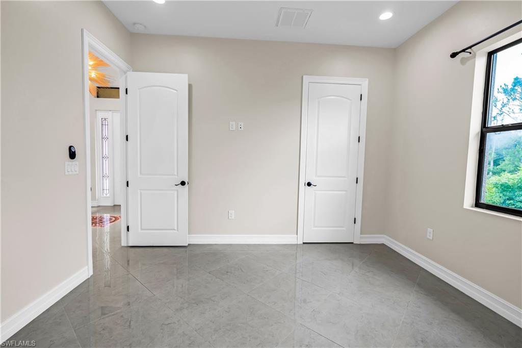 Room featuring light-toned walls, high ceilings with recessed lighting, and a window providing natural light