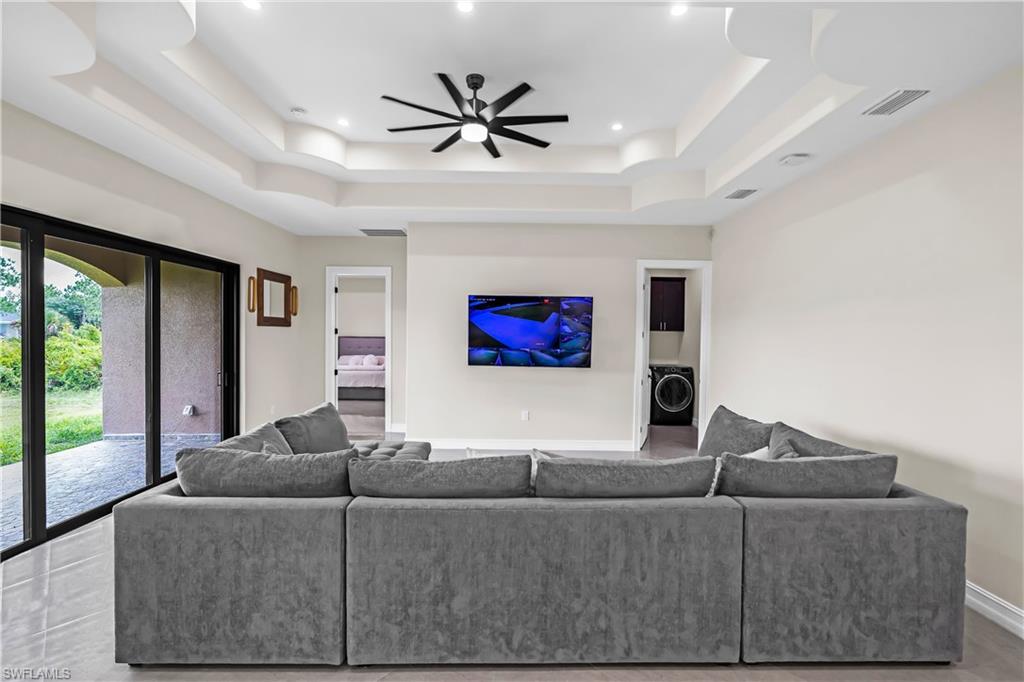 Recessed lighting and a contemporary ceiling fan illuminate the tiered tray ceiling