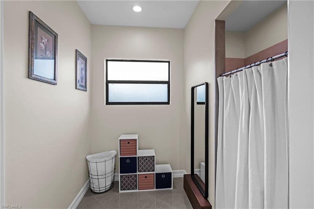 Bathroom featuring a frosted window with dark trim, recessed ceiling lighting, and tile flooring