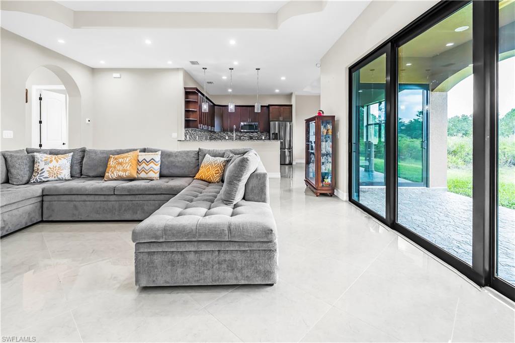 Spacious interior featuring large format light-toned tile flooring and expansive sliding glass doors