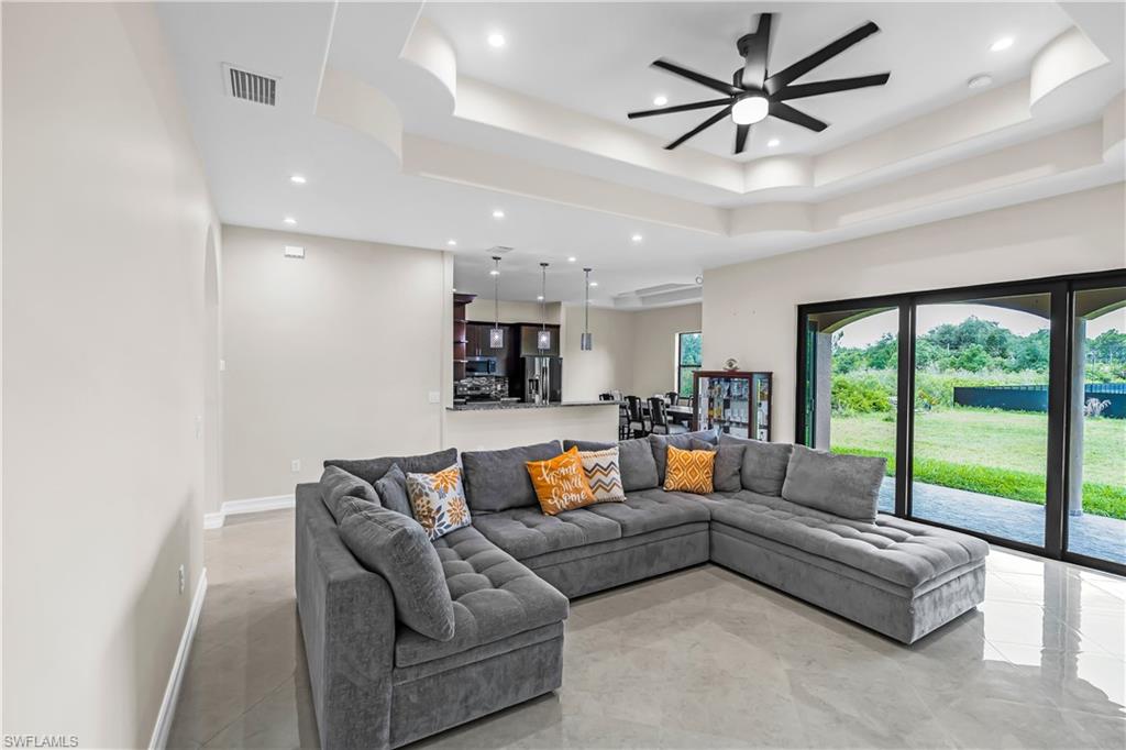 Spacious living area featuring coffered ceilings, recessed lighting, and large format tile flooring