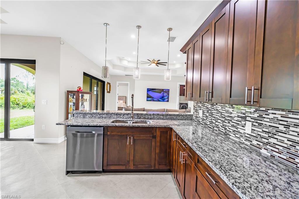 Kitchen featuring dark wood cabinetry, a stainless steel dishwasher, and granite countertops