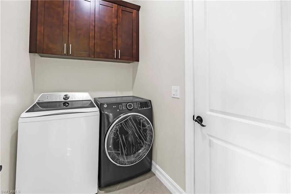 Dedicated laundry area featuring dark wood-finish cabinetry with brushed nickel hardware