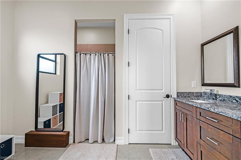 Bathroom featuring a vanity with wood-finish cabinetry, a stone countertop, and a rectangular undermount sink