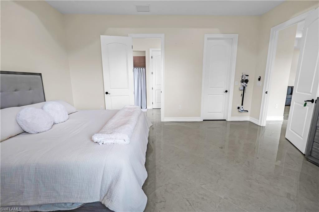 Spacious room featuring light-toned walls, high ceilings, polished tile flooring, and multiple white panel doors with black hardware