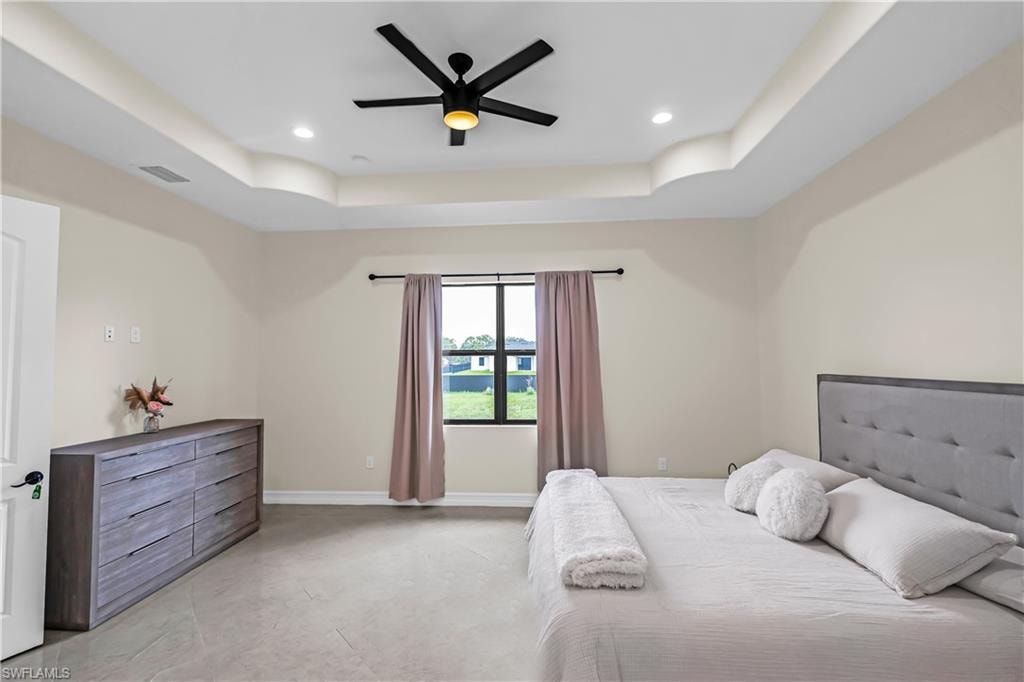 Spacious room featuring a tray ceiling with recessed lighting and a ceiling fan