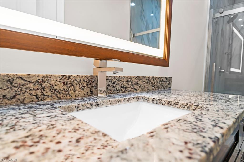 Vanity with an integrated rectangular sink, speckled stone countertop, and a contemporary brushed nickel faucet