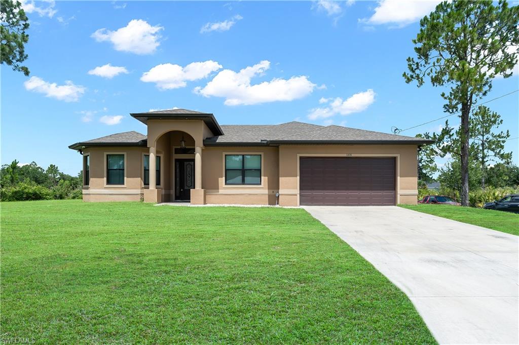 Stucco exterior residence featuring an arched portico entry, a two-car garage with a brown door, and a concrete driveway