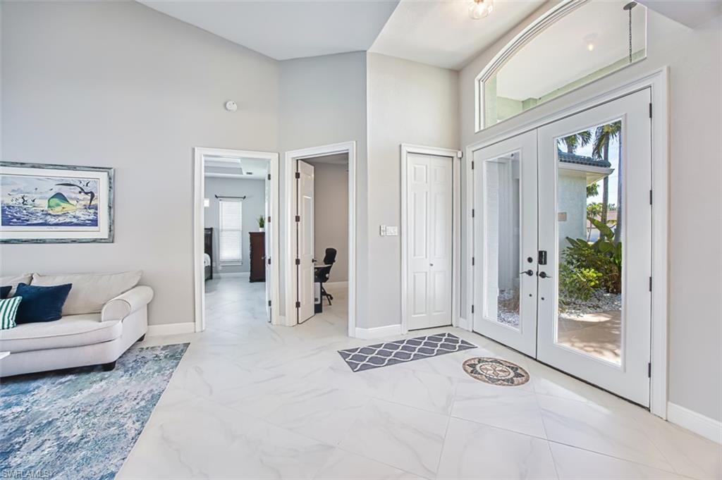 Entryway featuring french doors, healthy amount of natural light, a high ceiling, and light marble finish floors