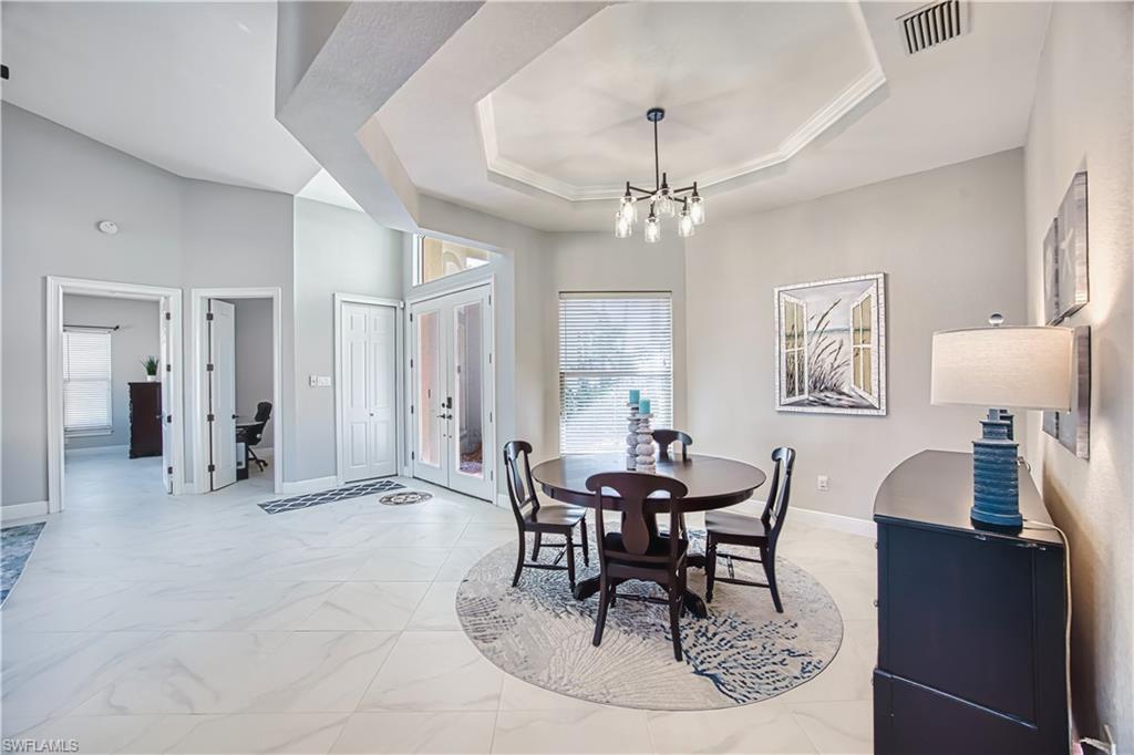 Dining space with a raised ceiling, light marble finish floors, and suspended lighting