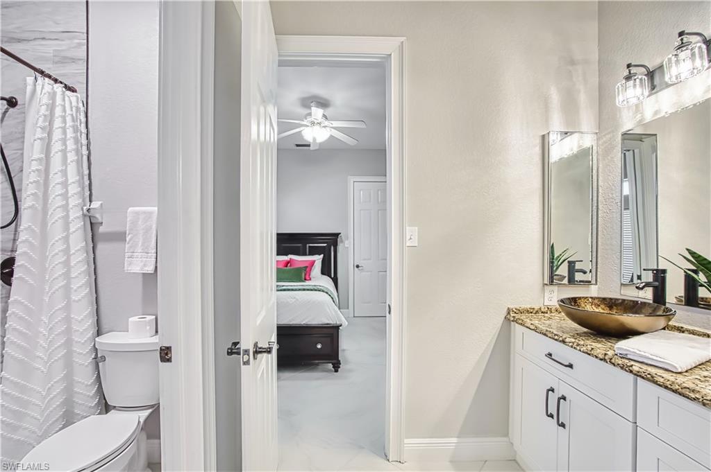 Ensuite bathroom featuring vanity, a textured wall, a shower with shower curtain, and ceiling fan
