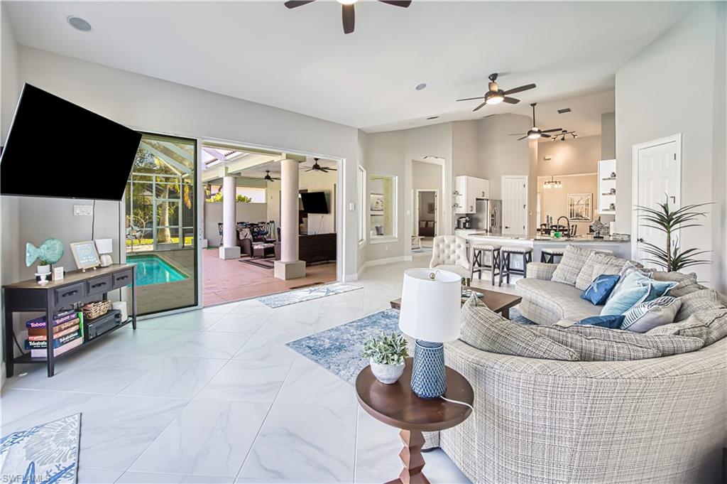 Living room featuring a sunroom, a ceiling fan, and vaulted ceiling