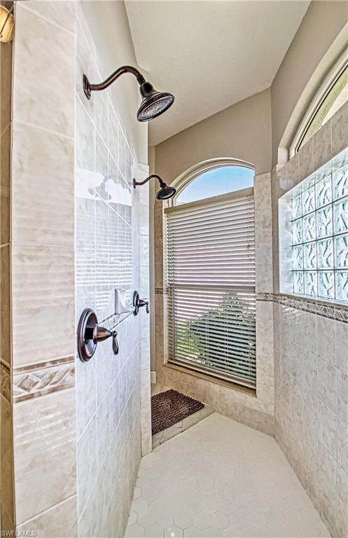 Bathroom with tiled shower, light tile patterned flooring, and tile walls