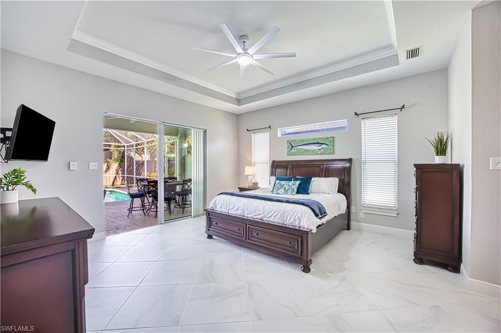 Bedroom with a sunroom, ceiling fan, access to exterior, light marble finish floors, and multiple windows
