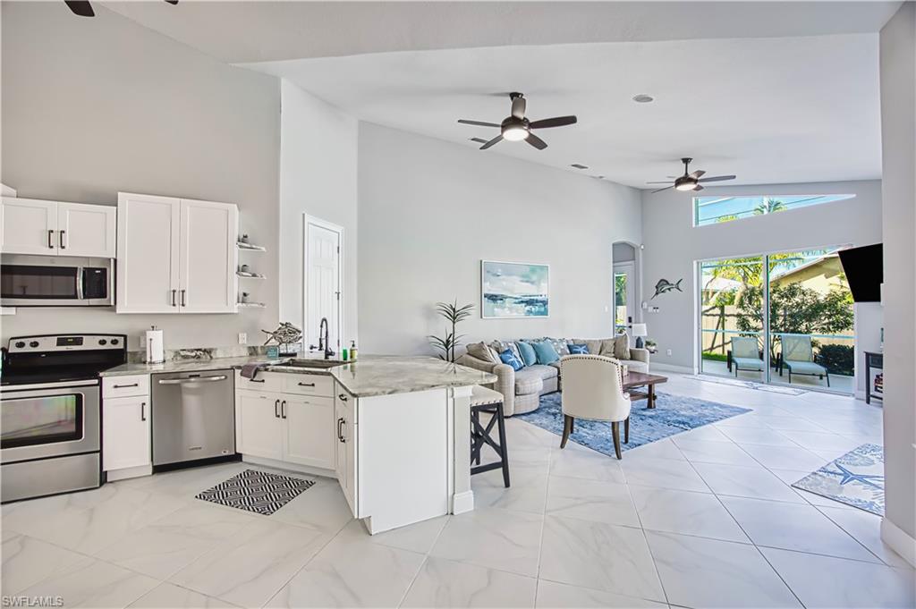 Kitchen featuring ceiling fan, open floor plan, a peninsula, stainless steel appliances, and a breakfast bar area