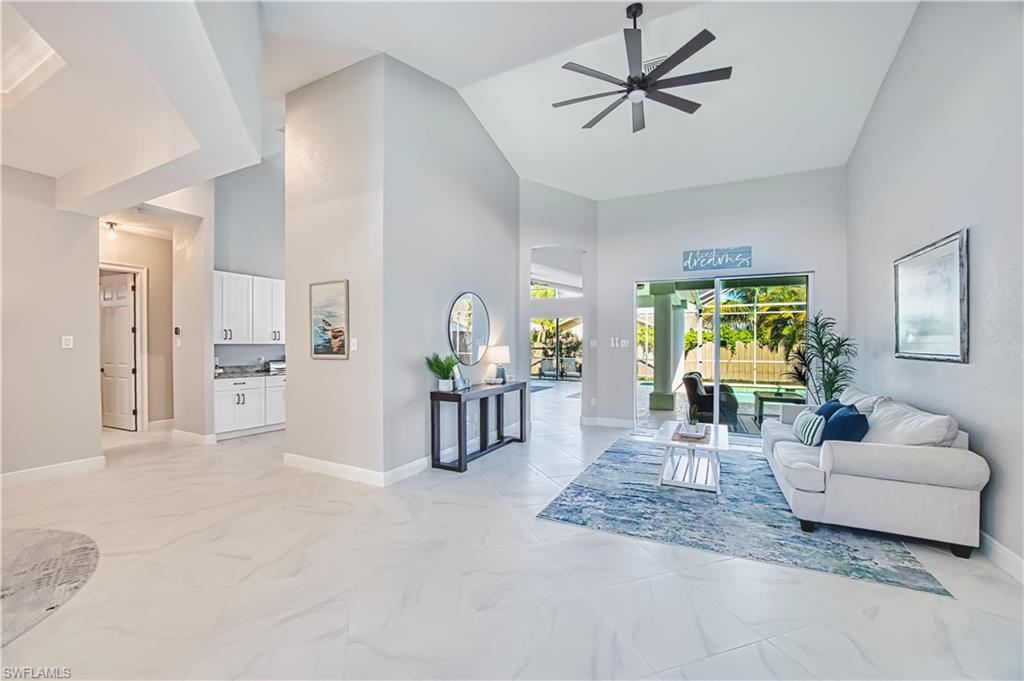 Living room with ceiling fan, arched walkways, and lofted ceiling
