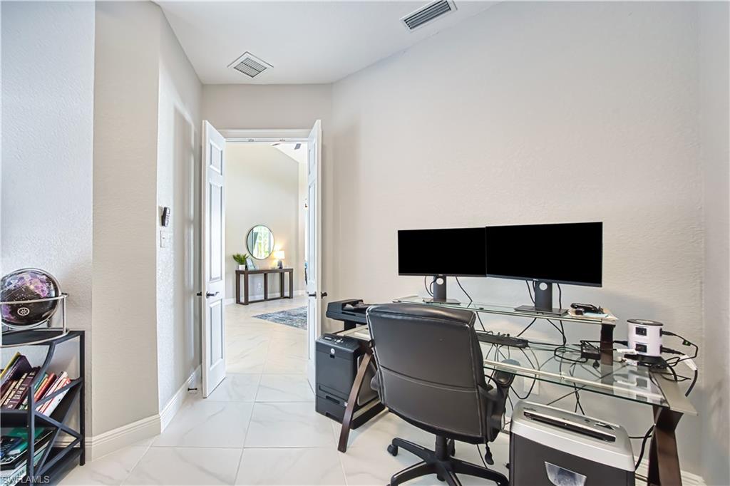 Office space with light marble finish floors and a textured wall