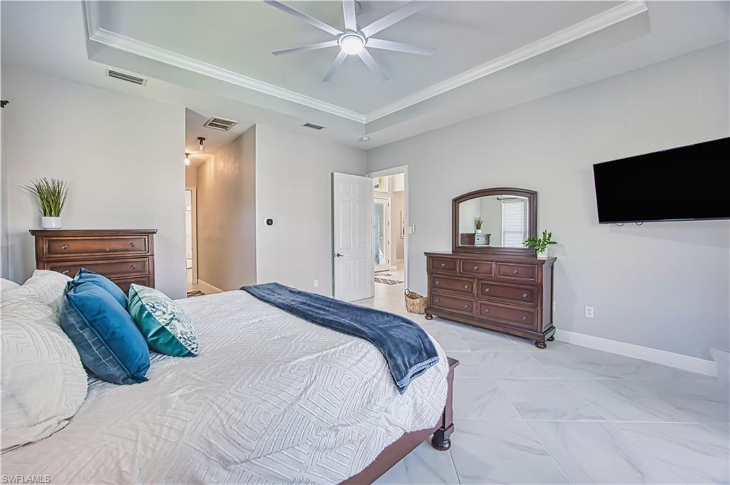 Bedroom with a tray ceiling, ornamental molding, and a ceiling fan
