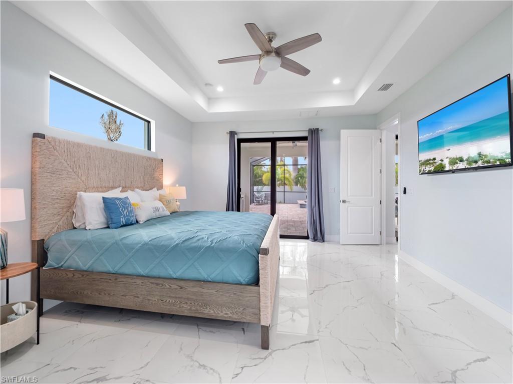 Bedroom with access to outside, a tray ceiling, a ceiling fan, and recessed lighting
