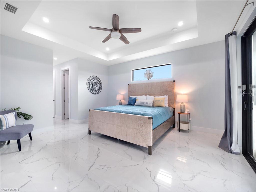 Bedroom with a ceiling fan, recessed lighting, a raised ceiling, and light marble finish floors