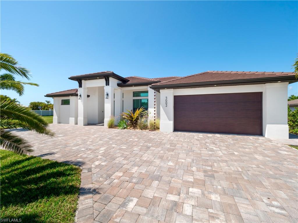 Prairie-style house with an attached garage, decorative driveway, stucco siding, and a tiled roof
