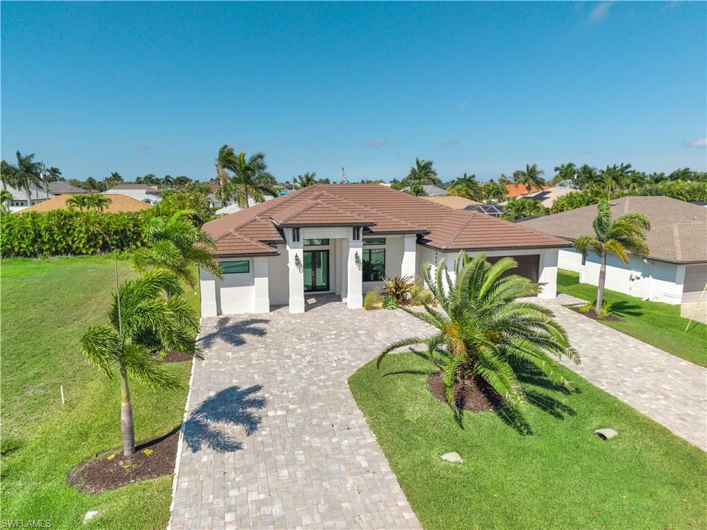 Mediterranean / spanish-style home featuring stucco siding, a front lawn, a tile roof, and an attached garage