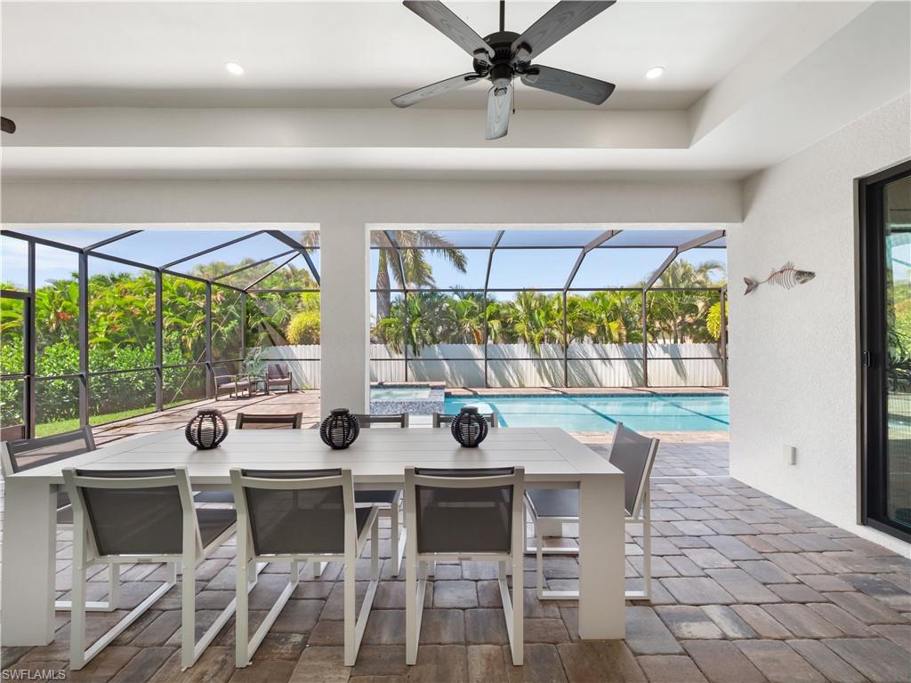 View of patio with a sunroom, outdoor dining space, glass enclosure, and a pool with connected hot tub