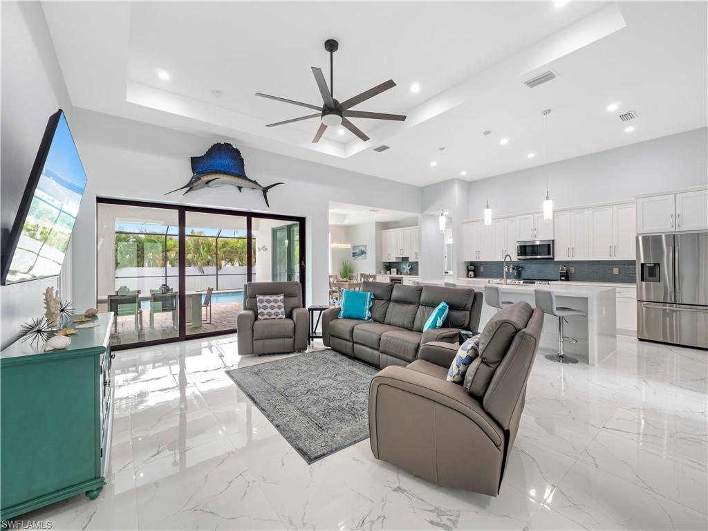 Living area featuring a ceiling fan, a high ceiling, light marble finish flooring, and recessed lighting