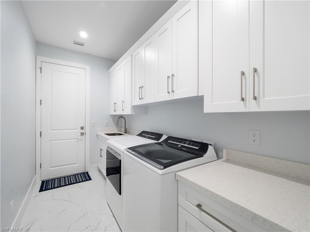 Laundry room with light marble finish floors, cabinet space, washer and dryer, and recessed lighting