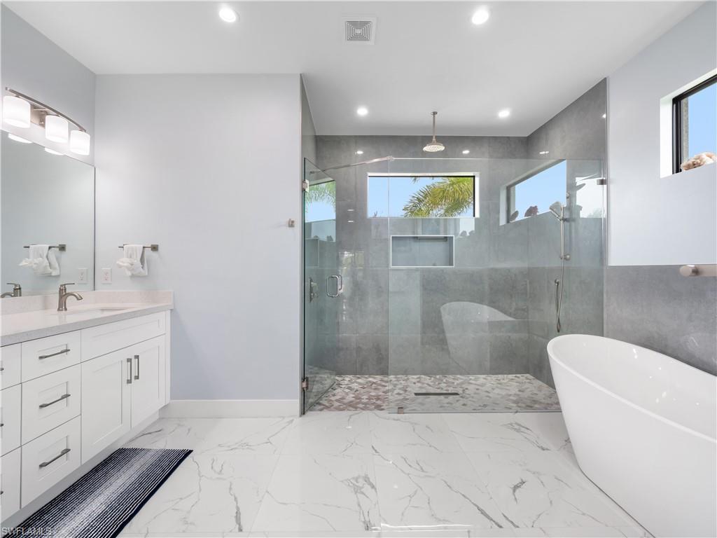 Bathroom featuring a soaking tub, vanity, a shower stall, recessed lighting, and light marble finish floors
