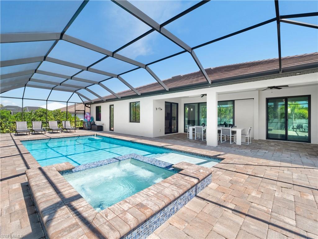 Integrated pool / hot tub featuring a sunroom, a patio area, outdoor dining area, and a lanai