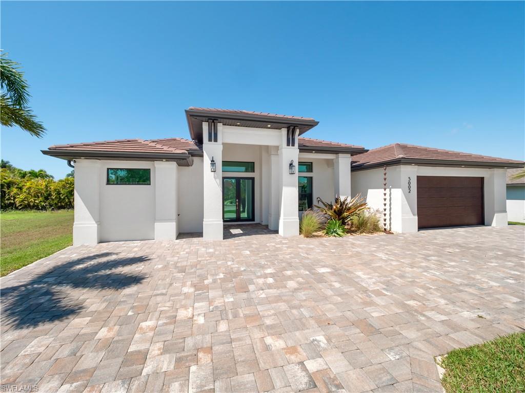 Prairie-style house with stucco siding, a garage, a tile roof, and driveway