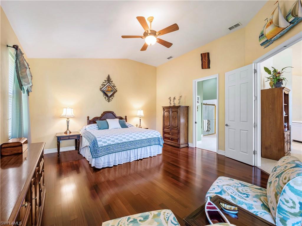 Bedroom with dark wood-style flooring, a ceiling fan, and vaulted ceiling