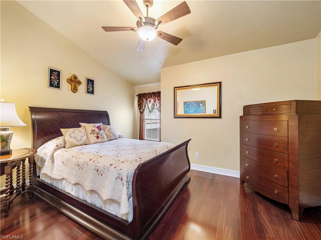 Bedroom with dark wood-style flooring, a ceiling fan, and vaulted ceiling