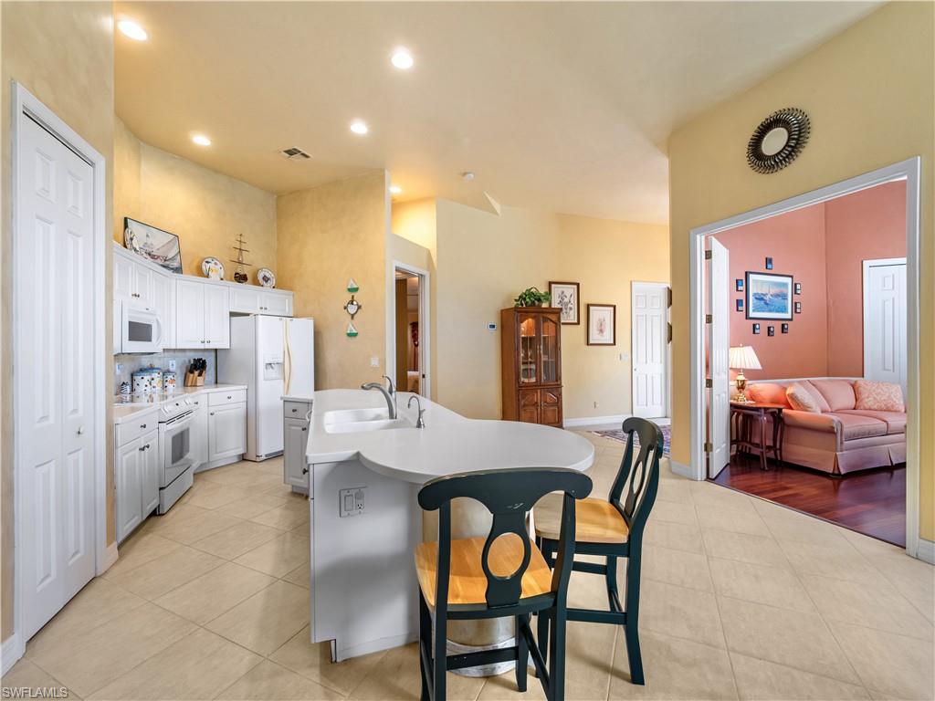 Kitchen featuring a kitchen bar, light countertops, a kitchen island with sink, light tile patterned floors, and recessed lighting