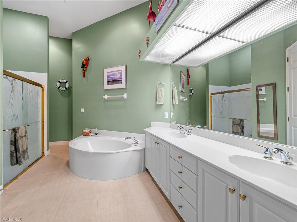 Full bath featuring double vanity, a shower stall, and a bath