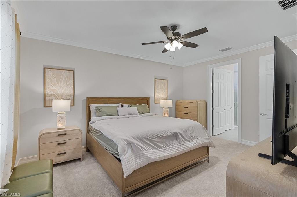 Bedroom featuring ceiling fan, a closet, light colored carpet, and ornamental molding